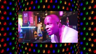 man sat in event venue overlaid on colourful background