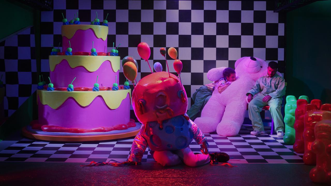 a giant teddy bear, a giant cake, and an alien in a dark room