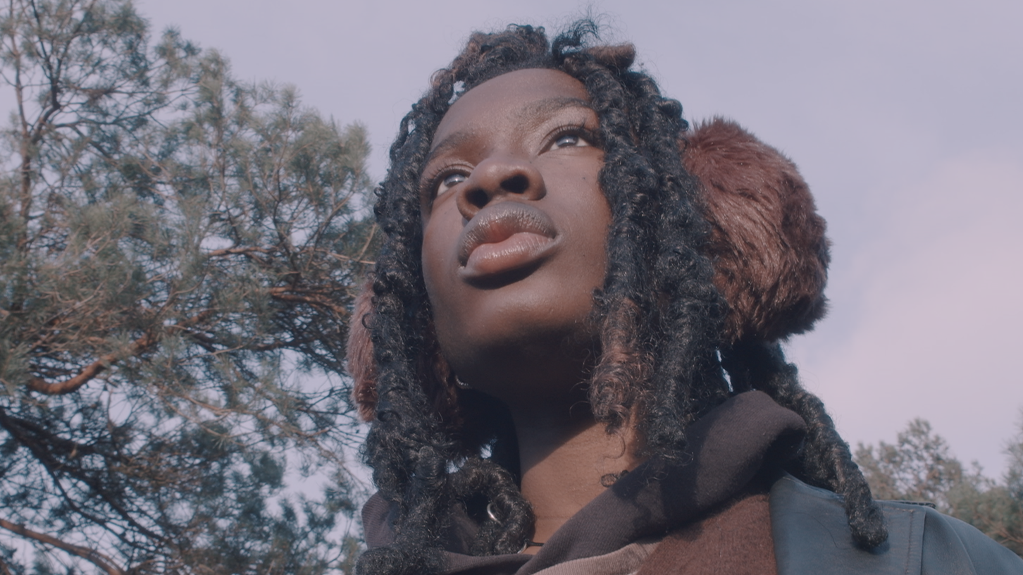 short film still of person in front of trees