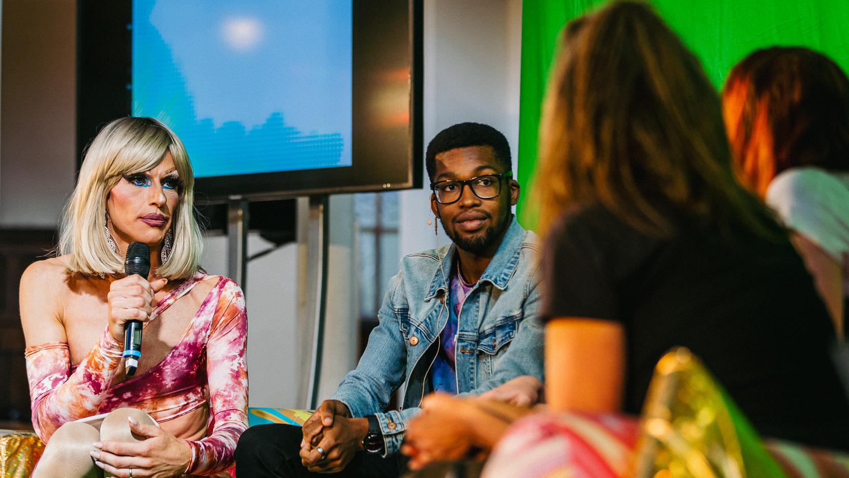 people sat on sofa talking with screen in background