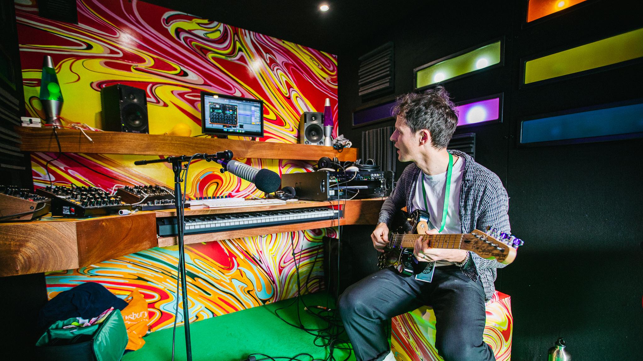 man playing guitar inside recording studio