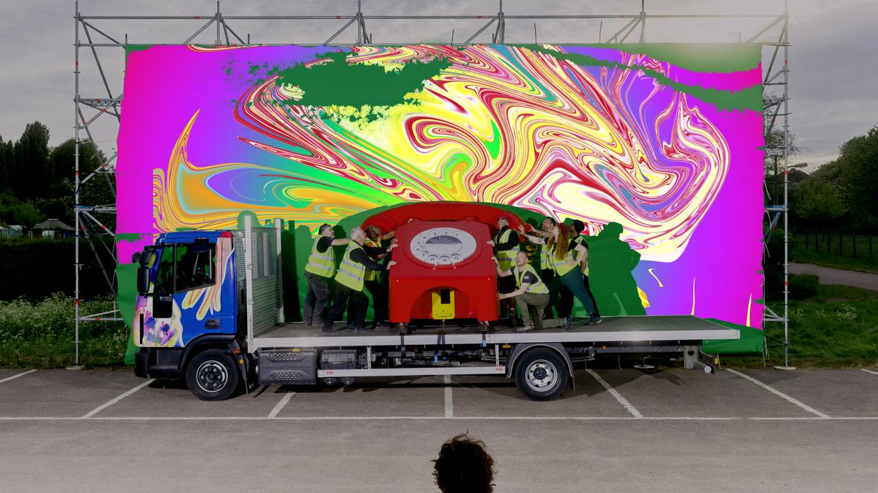 giant red telephone on a truck in front of a colourful background